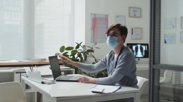 Jonge Vrouwelijke Arts Beschermend Masker Vouwen Laptop Uitnodigen Moslim Patiënt — Stockvideo