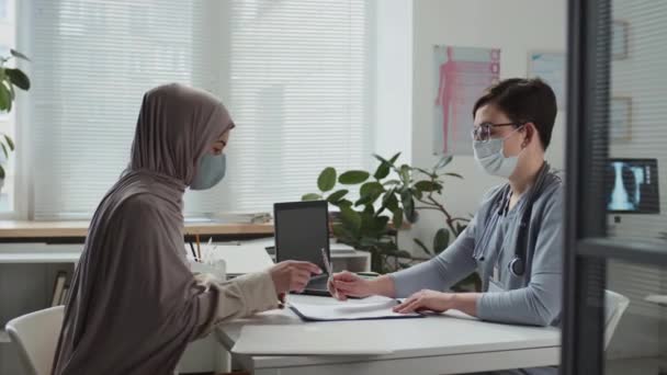 제복을 마스크를 의료진 병원에서 상담을 서명을 히잡을 이슬람 환자에게 문서를 — 비디오