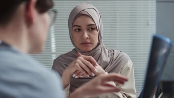 在诊所会诊期间 年轻的穆斯林女性头巾患者会聆听临床医生解释X光图像的细节 以及肺或胸部的医疗检查结果 — 图库视频影像