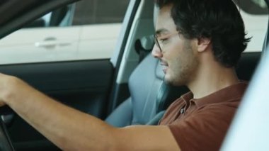 Orta boy, Orta Doğulu genç bir adamın direksiyonda oturarak yeni bir araba seçmesi.