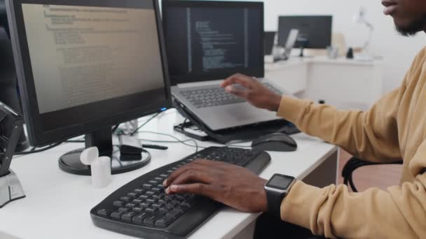 사무실에서 일하는 아프리카 미국인 남성의 데스크 컴퓨터와 노트북을 사용하여 데이터를 — 비디오