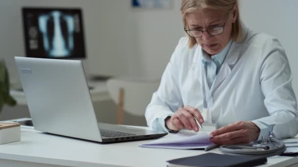 Σοβαρή Γυναίκα Κλινικός Εργαστηριακή Ποδιά Που Ψάχνει Μέσω Ιατρικού Εγγράφου — Αρχείο Βίντεο