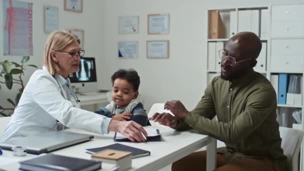 Mature Pediatrician Passing Medical Document Signing Father Little Boy While — Stock Video