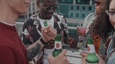 Çağdaş Z erkek ve kadın grupları çatıdaki partide içki şişeleri ve bardaklarla dans ediyorlar.