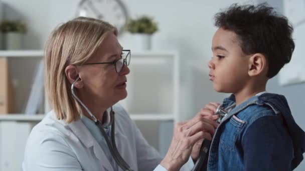 Glückliche Reife Kinderärztin Mit Stethoskop Die Den Niedlichen Kleinen Jungen — Stockvideo