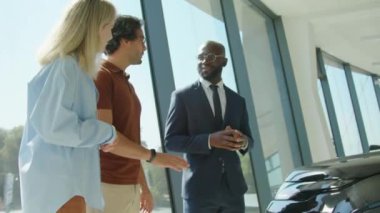 Araba galerisinde çalışan takım elbiseli Afrikalı Amerikalı bir satıcının müşteri danışmanlığıyla el sıkışması.