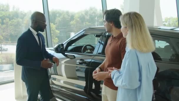 Чорний Чоловік Костюмі Працює Автосалоні Відкриває Двері Транспортування Автомобілів Пропонує — стокове відео