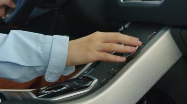 Genç, beyaz bir kadının galeride yeni bir araba seçerken ön koltukta otururken ve iç ve ön panelini keşfederken yakın plan çekimleri.