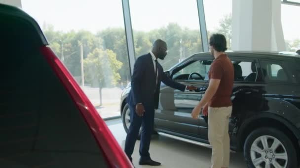 Długie Ujęcie Afroamerykańskiego Sprzedawcy Pracującego Potencjalnym Nabywcą Nowoczesnym Salonie Samochodowym — Wideo stockowe