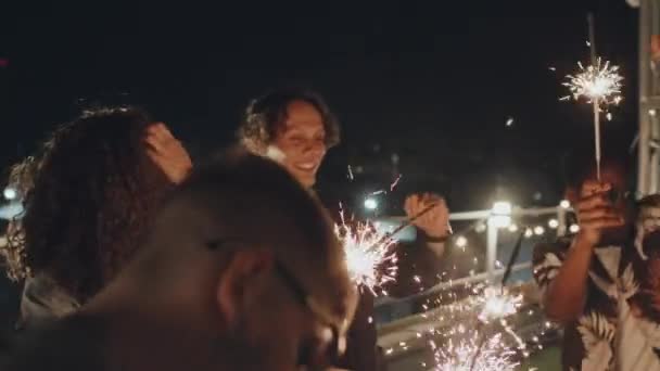 男子和女子身着休闲装 手握火焰喷射器 在夜间屋顶派对上跳舞的慢镜头 — 图库视频影像