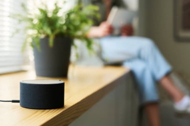 Arka planda dijital tablet kullanan bir kadınla evde müzik dinlemek için akıllı konuşmacının yakın plan görüntüsü