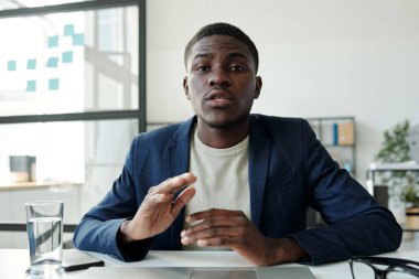 Genç, kendine güvenen bir borsacı ya da avukat bilgisayarın önünde otururken görüntülü konuşma sırasında müşteriye bir şey anlatıyor.