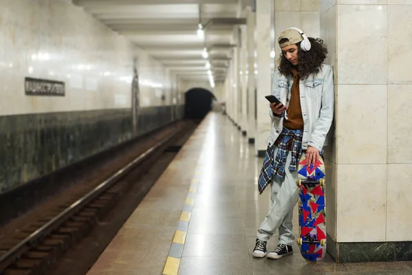 헤드폰을 음악을 지하철을 기다리면서 스마트폰으로 플레이 리스트를 — 스톡 사진