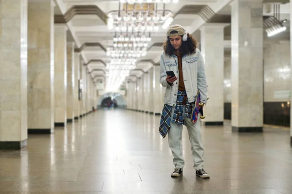 Denim 남성은 지하철 터널에 운송을 기다리는 휴대폰으로 메시지를 교환한다 — 스톡 사진