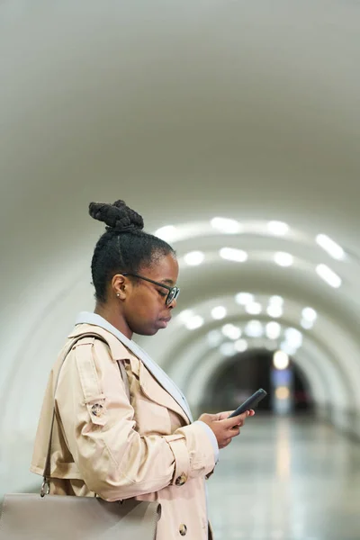 穿着时髦风衣的年轻女商人站在地铁隧道前 用手机拍摄的简况 — 图库照片