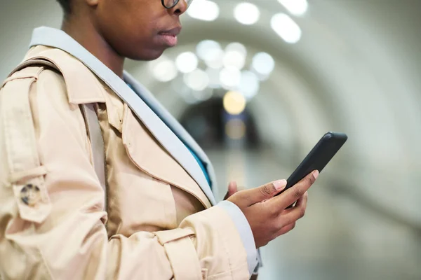 身着米色风衣 手持智能手机 在地铁隧道镜头前发短信的黑人女性侧视图截图 — 图库照片