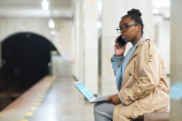 坐在地铁站等火车时 跪着用手机聊天的年轻女商人的侧影 — 图库照片