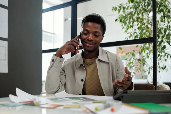 Молодой Афроамериканский Дизайнер Архитектор Разговаривает Мобильному Телефону Сидя Рабочем Месте — стоковое фото