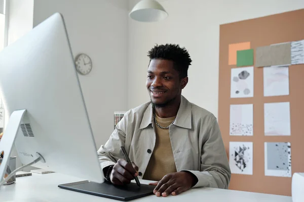 面带微笑的非裔美国男性平面设计师或带触控笔和触摸板的复习者 在办公室工作时看着电脑屏幕 — 图库照片