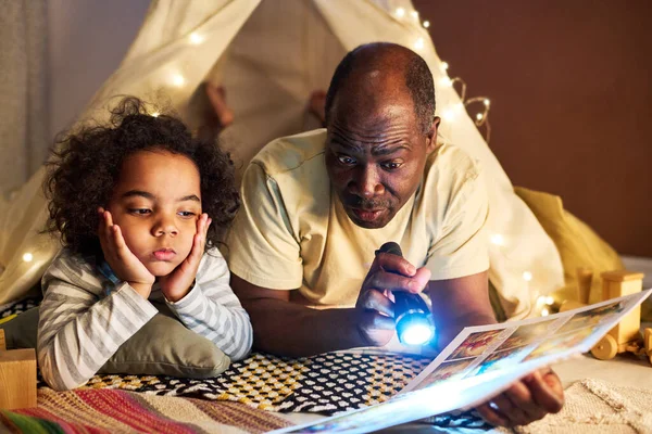 African American Dad Reading Book His Little Son Using Flashlight — Stock Photo, Image