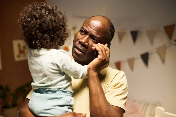 Grave Padre Afroamericano Ocupado Teléfono Mientras Está Sentado Con Bebé —  Fotos de Stock