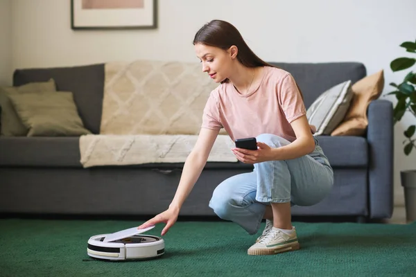 Young Woman Turning Robot Vacuum Cleaner Her Smartphone Housework — Stock Photo, Image