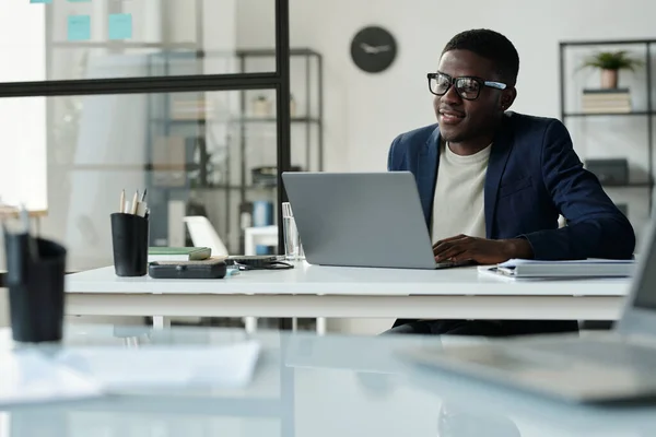 年轻的非洲裔美国经理穿着西装 坐在办公室的工作场所边 看着笔记本电脑屏幕边 一边通过视频聊天进行交流 — 图库照片