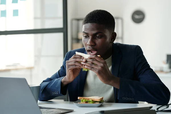 Joven Trabajador Oficina Hambriento Ropa Formal Anteojos Comiendo Sándwich Mirando —  Fotos de Stock