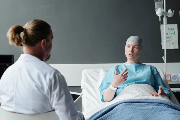 Mladá Pacientka Vysvětlující Zkušené Onkolog Její Symptomy Zatímco Sedí Posteli — Stock fotografie