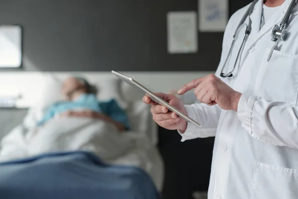 プレゼンテーション中や病院病棟の医療データを見ながらタブレット画面を指して成熟した経験豊富な医師の手 — ストック写真