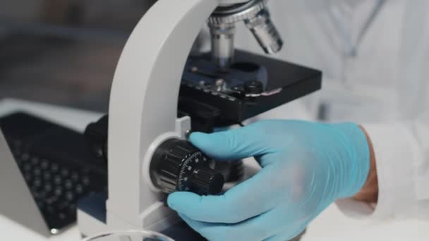 Mão Cientista Masculino Luvas Proteção Ajustando Discagem Microscópio Durante Investigação — Vídeo de Stock