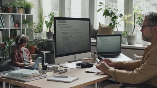사무실에서 자신의 직장에 컴퓨터에 코드와 성숙한 프로그래머 — 비디오