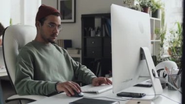 Bilgisayar programında çalışan genç geliştirici iş yerinde oturuyor.
