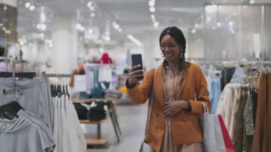 Alışveriş merkezinde yürürken internet üzerinden iletişim kuran Afro-Amerikalı bir kız.