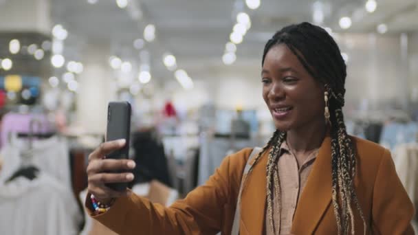 ショッピングモールで彼女のスマートフォンを使用してオンラインで彼女の友人と話すアフリカ系アメリカ人の女の子の中間閉鎖 — ストック動画