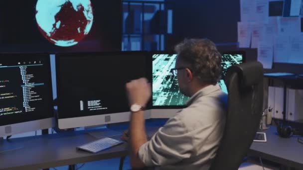 Задний Вид Зрелого Программиста Сидящего Столом Перед Мониторами Компьютера Работающего — стоковое видео