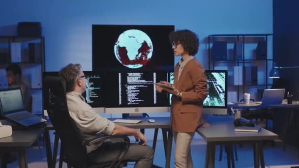 Коллеги Обсуждают Компьютерные Коды Мониторах Команде Время Работы Темном Офисе — стоковое видео