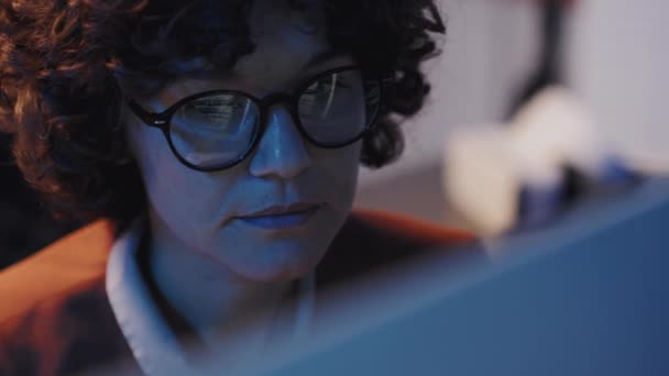 コンピュータ上の彼女のオンライン作業に集中眼鏡で若い女性の中型クローズアップショット — ストック動画