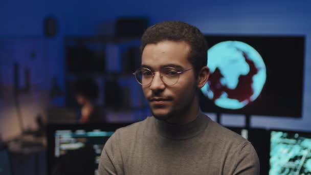 Itオフィスのソフトウェアでカメラを見ている眼鏡で若いプログラマーのミディアムクローズアップショット — ストック動画