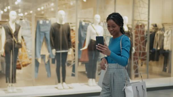Afroamerykanka Rozmawia Znajomym Online Smartfonie Podczas Robienia Zakupów Centrum Handlowym — Wideo stockowe