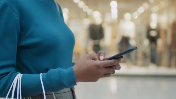 ショッピングモールに立っているスマートフォンでオンラインで通信するアフリカ系アメリカ人女性の閉鎖 — ストック動画