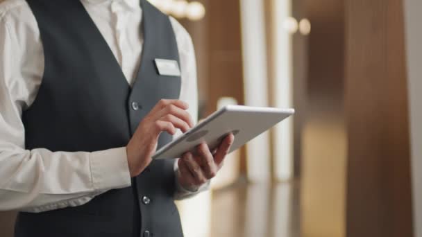 使用数码平板电脑 穿着制服站在大堂或休息室的中型酒店员工 — 图库视频影像