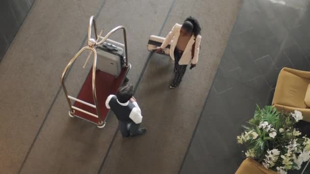 从上图可以看到 行李员穿着制服在豪华酒店工作 拿着新客人的行李箱 用行李车搬运 — 图库视频影像
