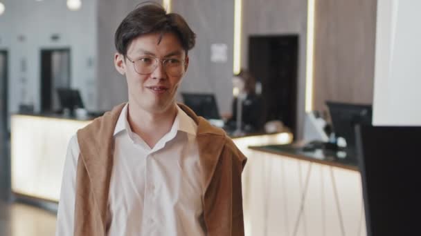 一位年轻的亚洲男子在现代宾馆里住得很舒服 接待员给了他一张钥匙卡 — 图库视频影像