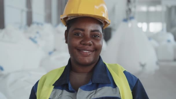 中特写慢镜头 描述快乐的非洲裔美国妇女戴着硬礼帽在工厂工作 看着相机 — 图库视频影像