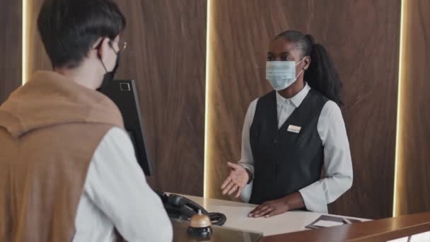 Selektivt Fokus Afroamerikansk Receptionist Bär Skyddsmask Berättar Gäst Hotellavdelningar Och — Stockvideo