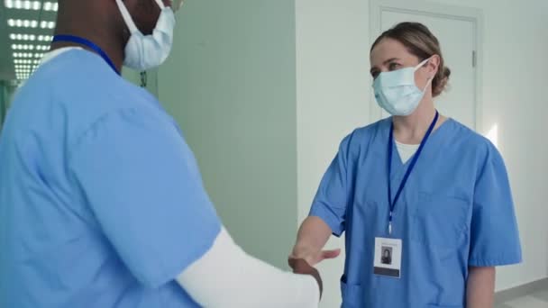 アフリカ系アメリカ人と白人医師のメディアショットが病院の廊下で握手して互いに挨拶 — ストック動画