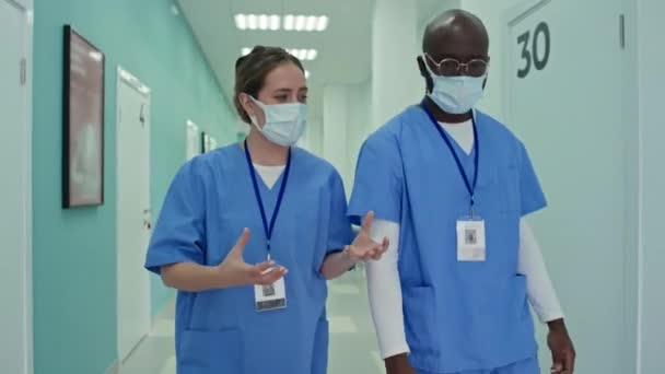 Rastreamento Dois Médicos Etnicamente Diversos Caminhando Longo Corredor Hospitalar Discutindo — Vídeo de Stock