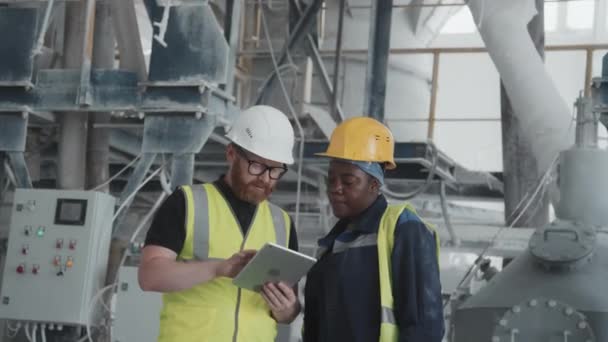 现代多元种族的工厂工人站在工业机器旁边检查数字平板电脑上的数据 — 图库视频影像