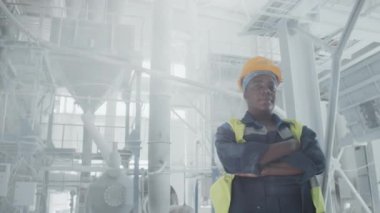 Başarılı Afrikalı Amerikalı kadın modern mermer fabrikasında çalışıyor. Kollarını kavuşturup kameraya bakıyor.